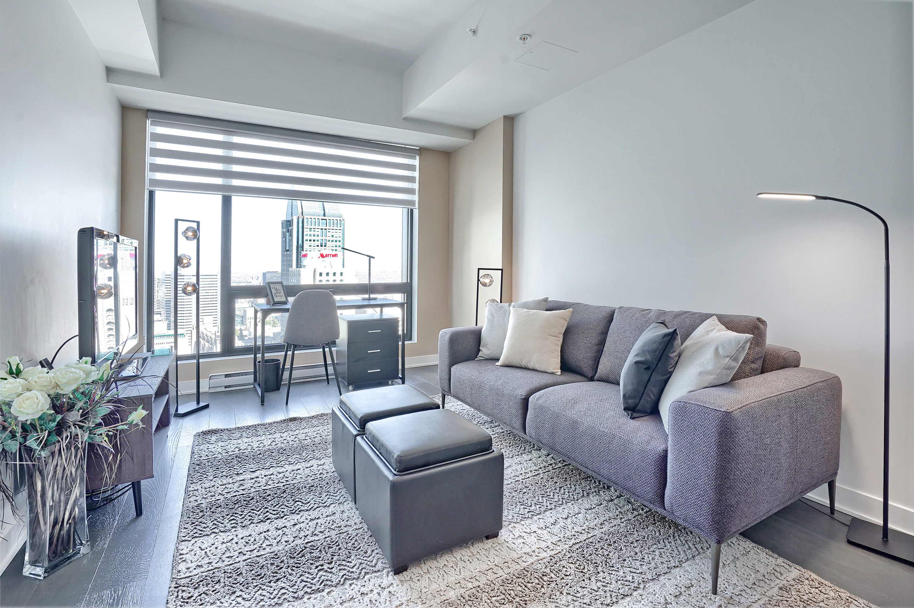 Spacious, bright, beautifully designed living area in this luxury furnished rental in montreal. Two large, floor-to-ceiling windows fills the room with sunlight. Plush leather furnishings, dining area for four, and a study desk and leather chair to match.