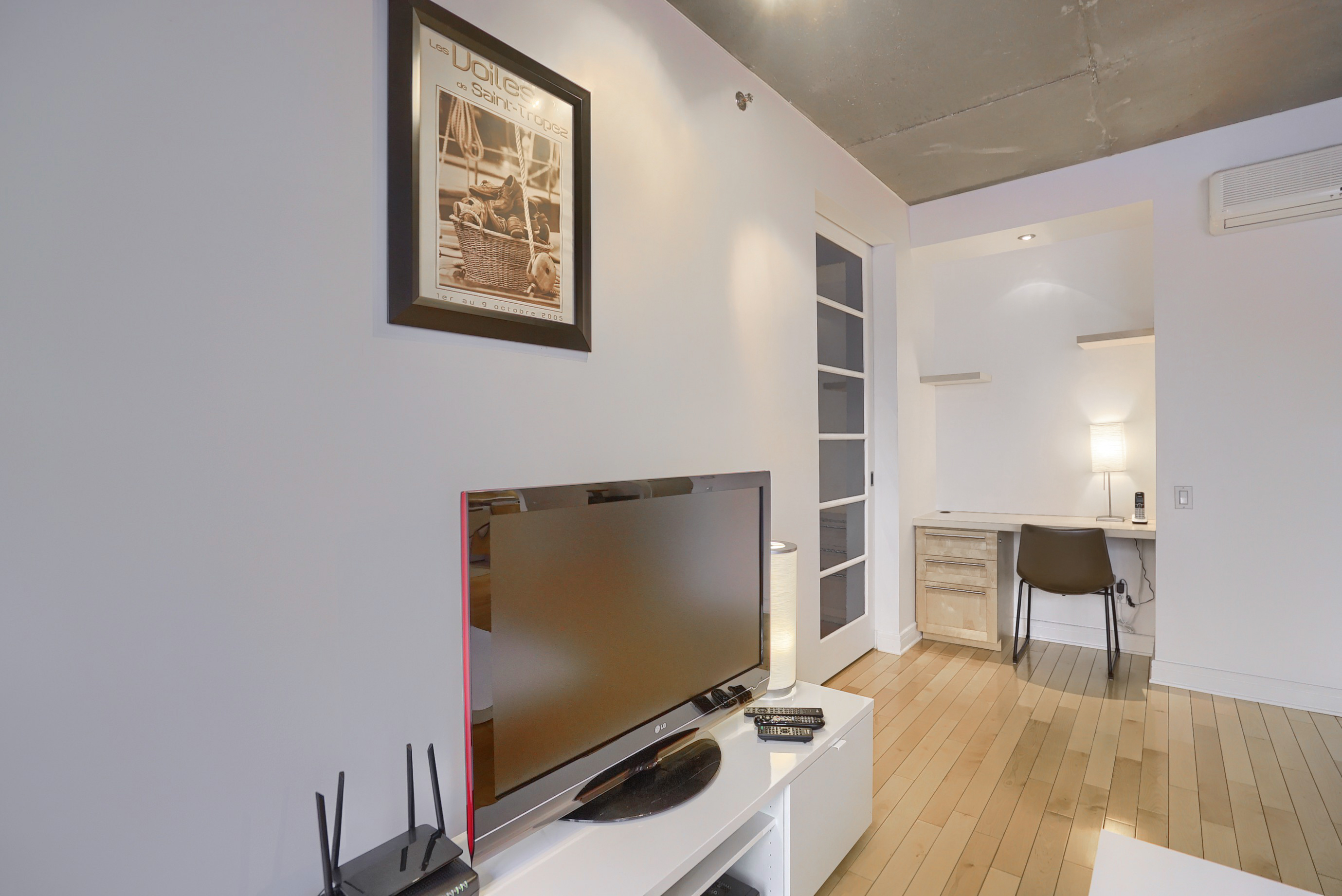 A living room with an HD-TV; a melamine finished cabinet, minimalist handles and a very well-defined cut with spacious storage. A spacious and well-equipped office, in our rental Short-Term Montreal