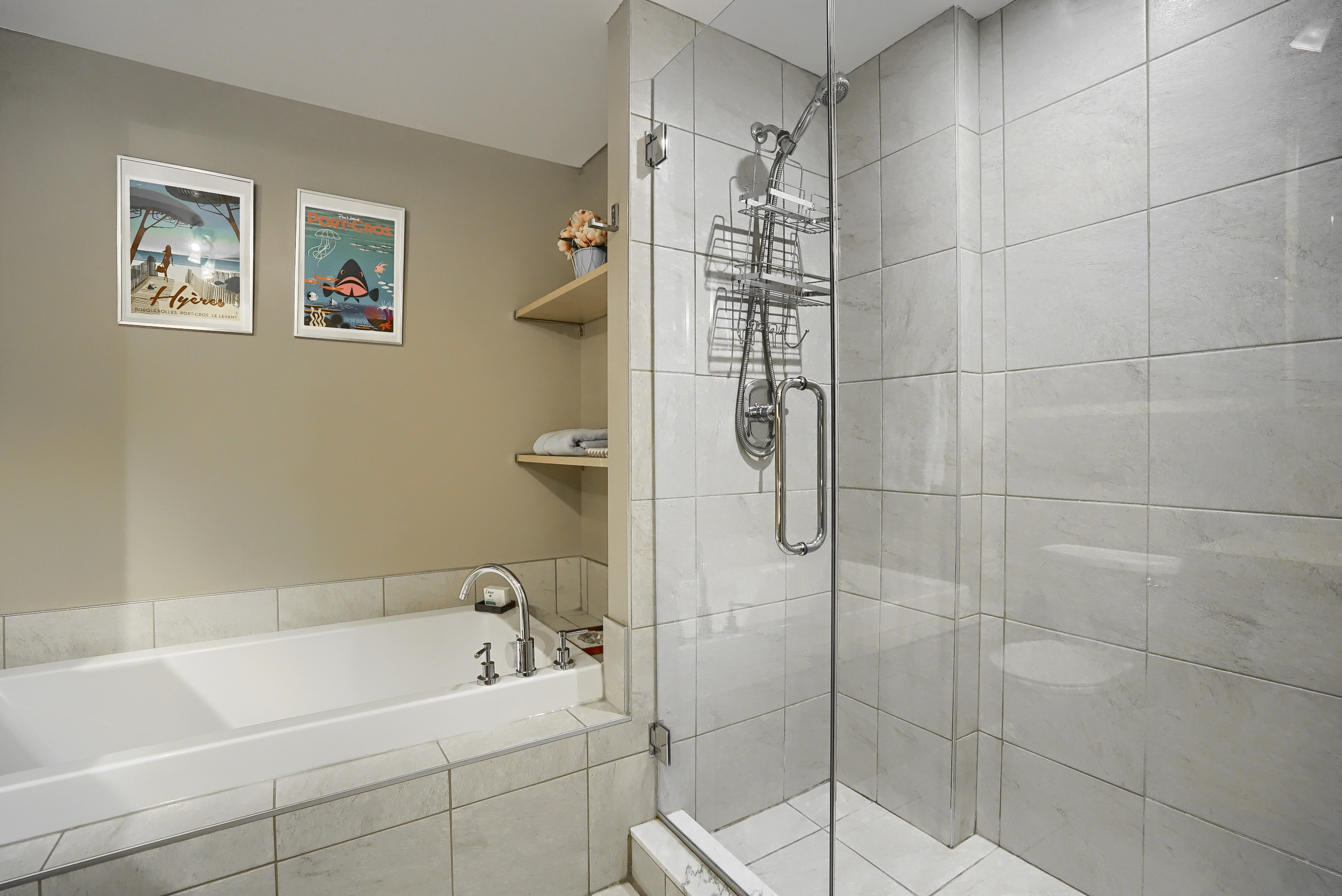 View of the bathroom showing the shower and the large bathtub. Glass shower, stainless steel shower head in this apartment for short term rent Montreal