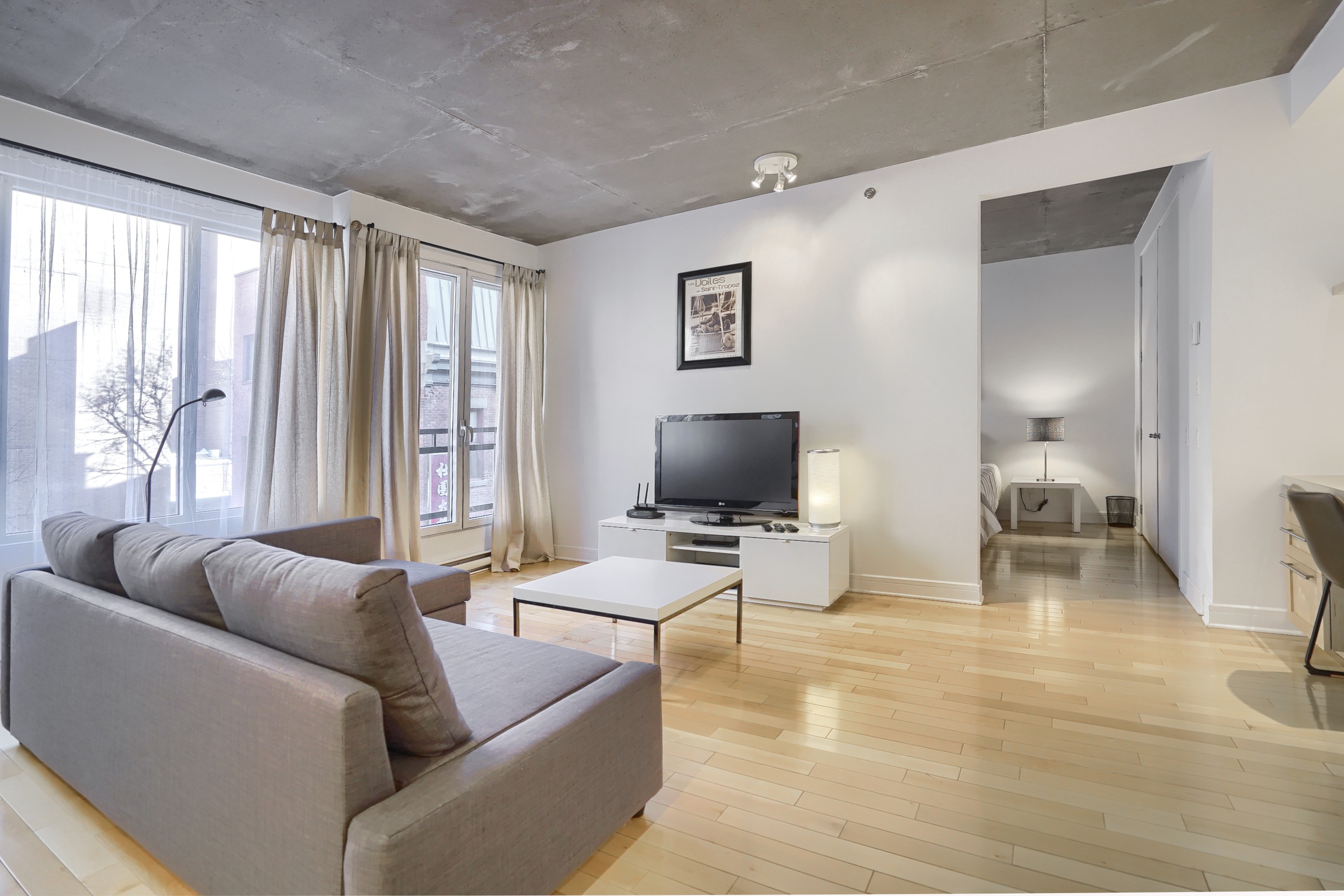 Here is a spectacular and very spacious, fully equipped living room with large, bright and sunny windows in our corporate housing in Montreal.