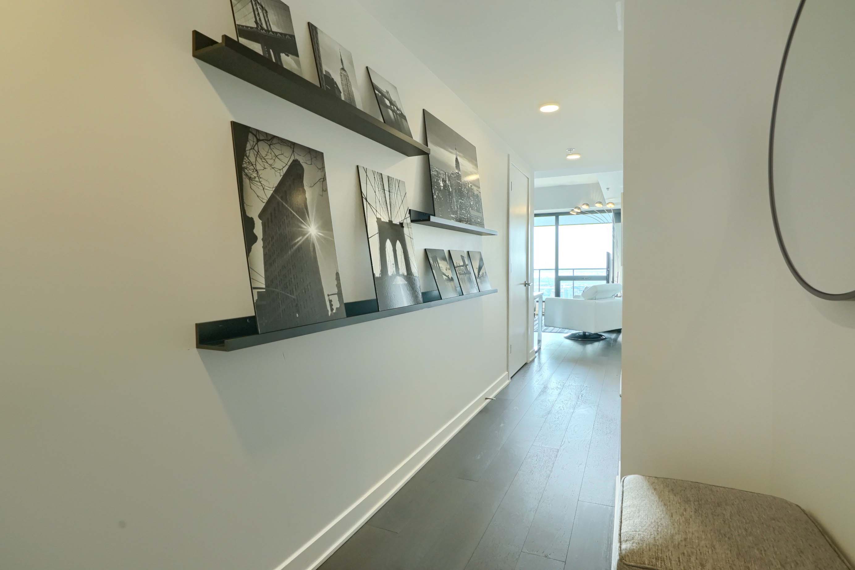 View of the hall from the door leading into this luxury furnished condo for rent in montreal. Designer accent wall with stunning photography and overhead lighting