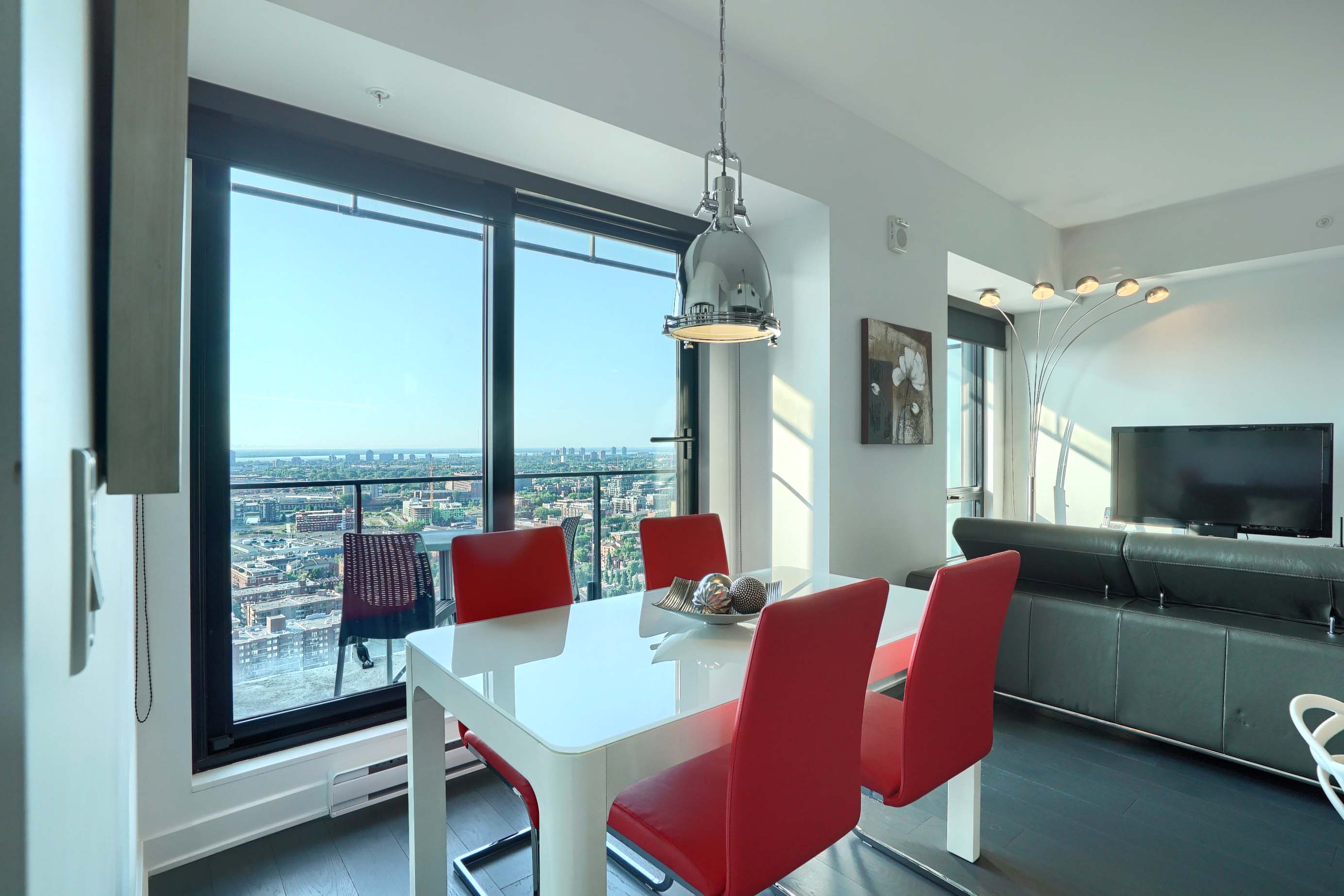 View of the dining table with seating for four, the balcony area and into the living area of this furnished short term rental in montreal