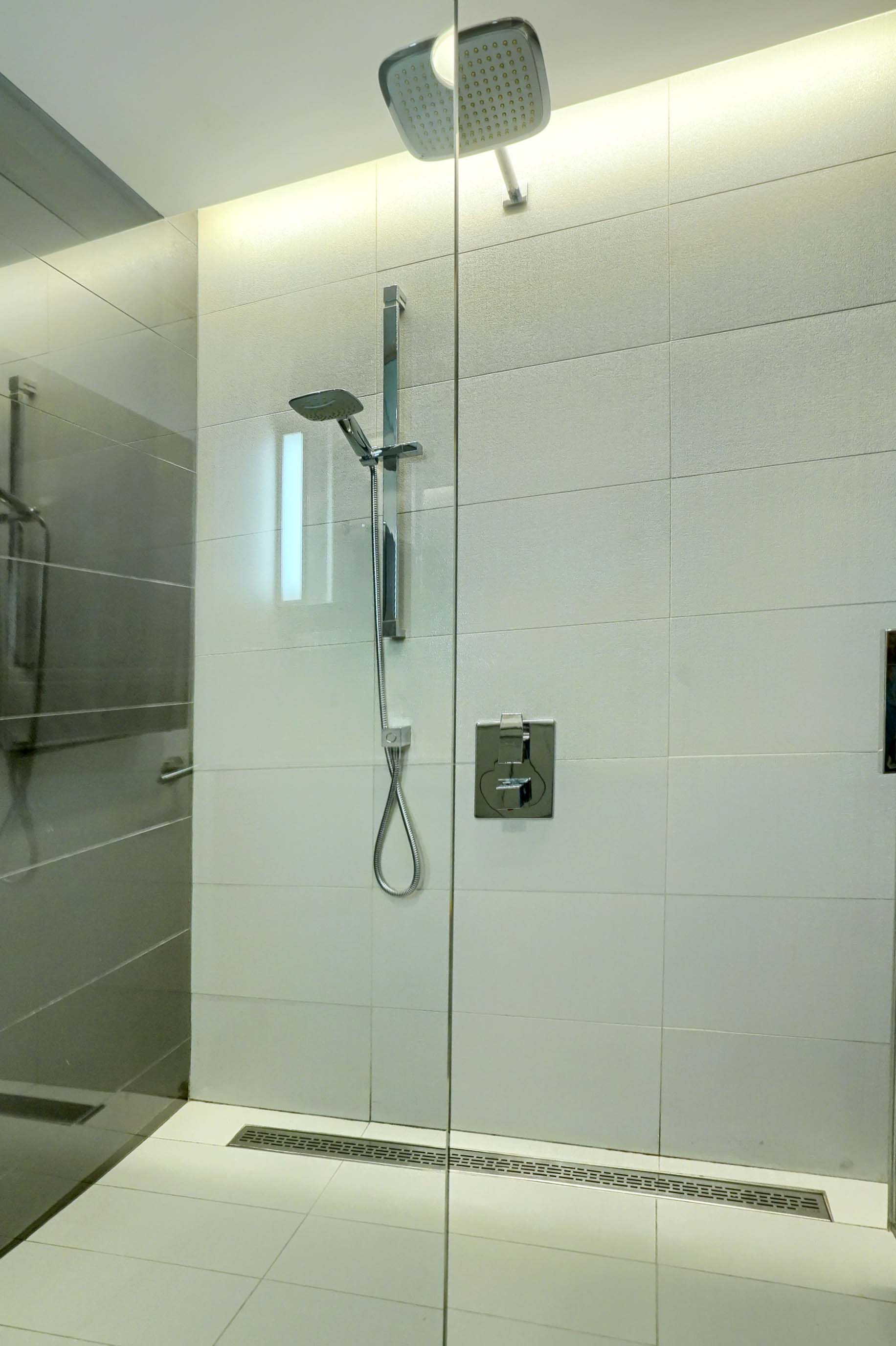 Close-up of the floor-to-ceiling glass shower with adjustable shower head in this ultra modern luxury furnished rental, short term, in montreal