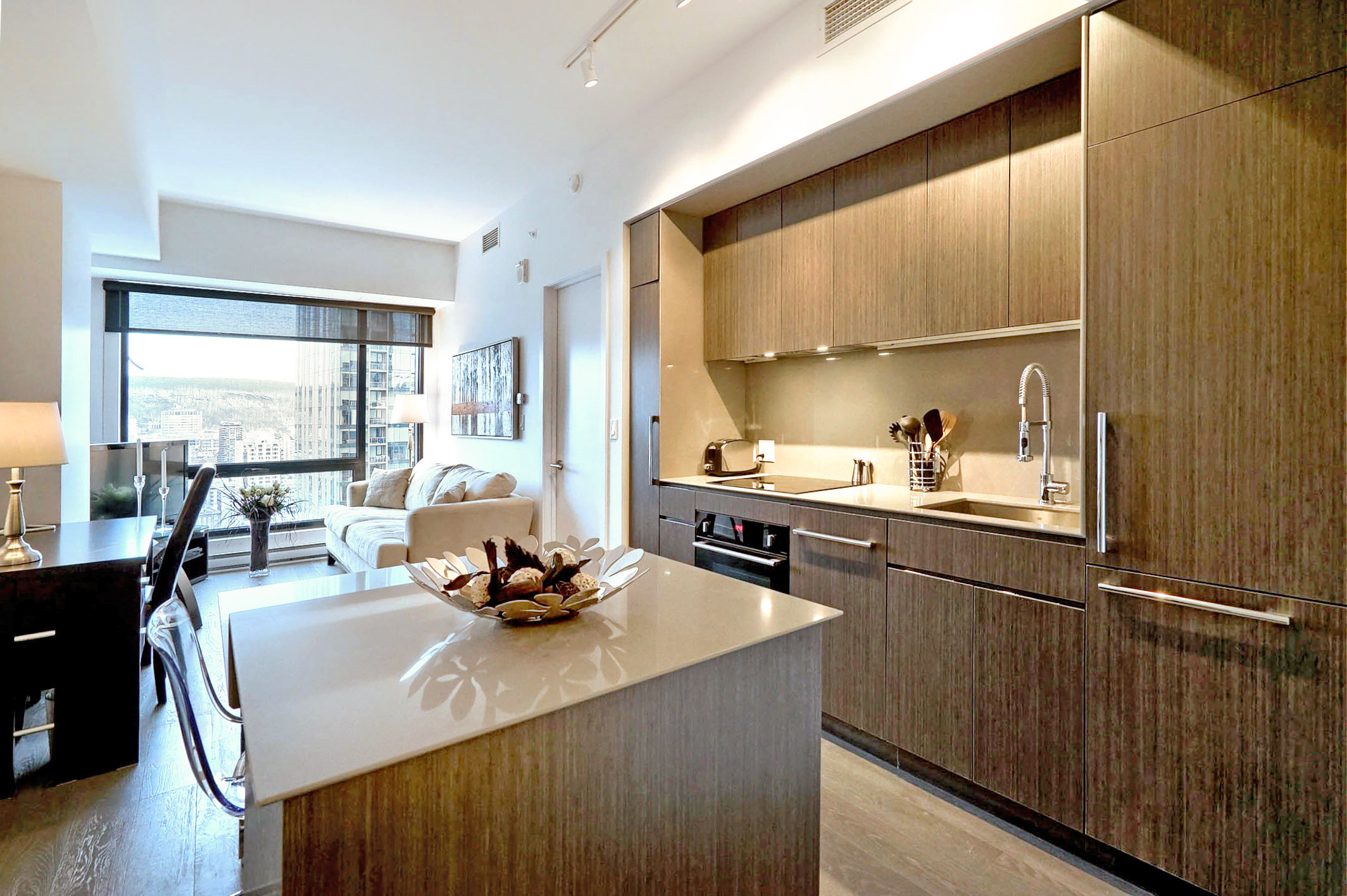 Angled view of the kitchen showing the refrigerator, sink and oven/stove. Bright and modern in this furnished corporate housing apartment in Montreal