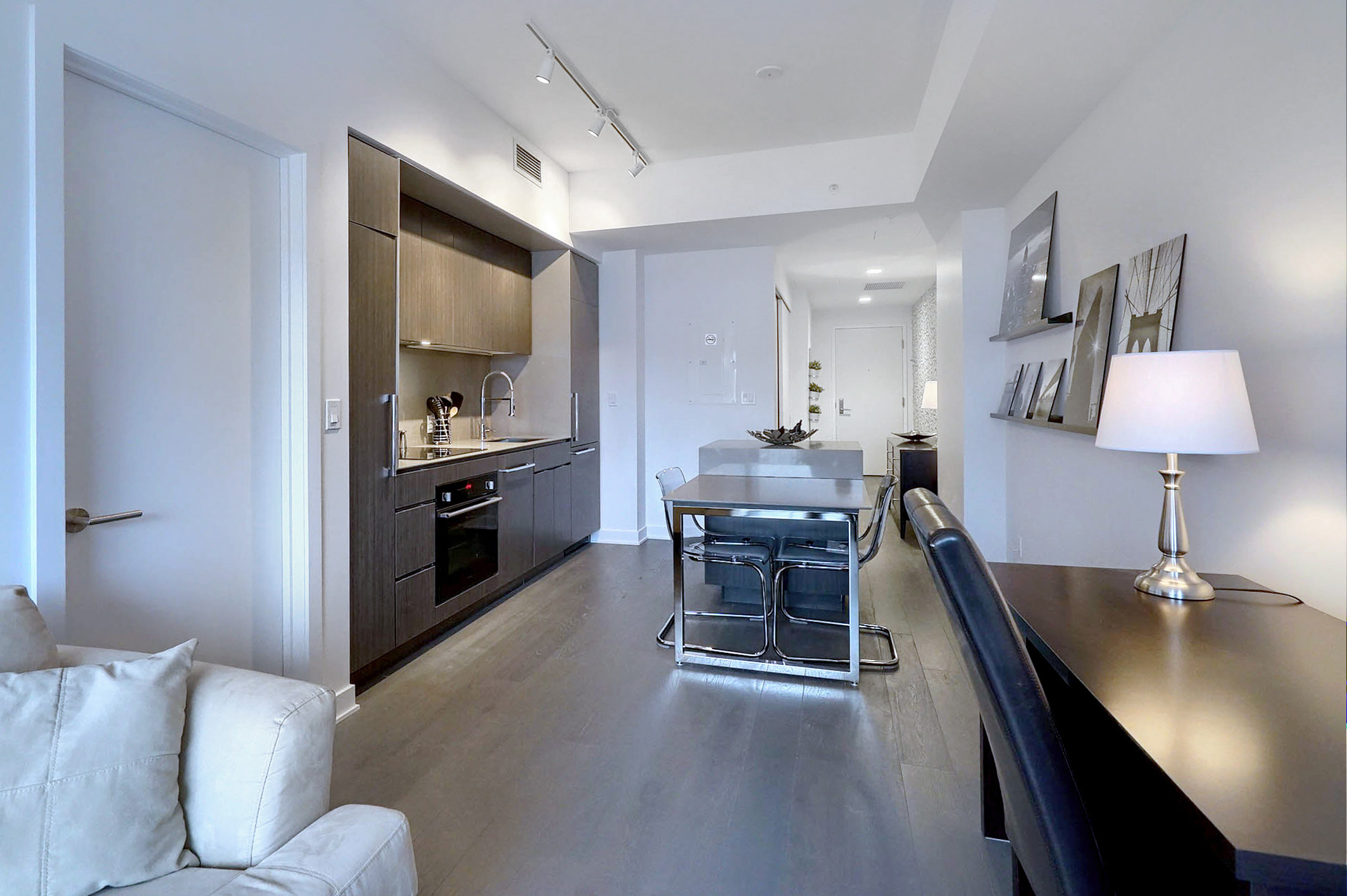 Wide view of the entire kitchen of this furnished executive housing apartment in Montreal. Beautiful, sleek cabinetry, darker wood flooring, plus office space to work comfortably from home