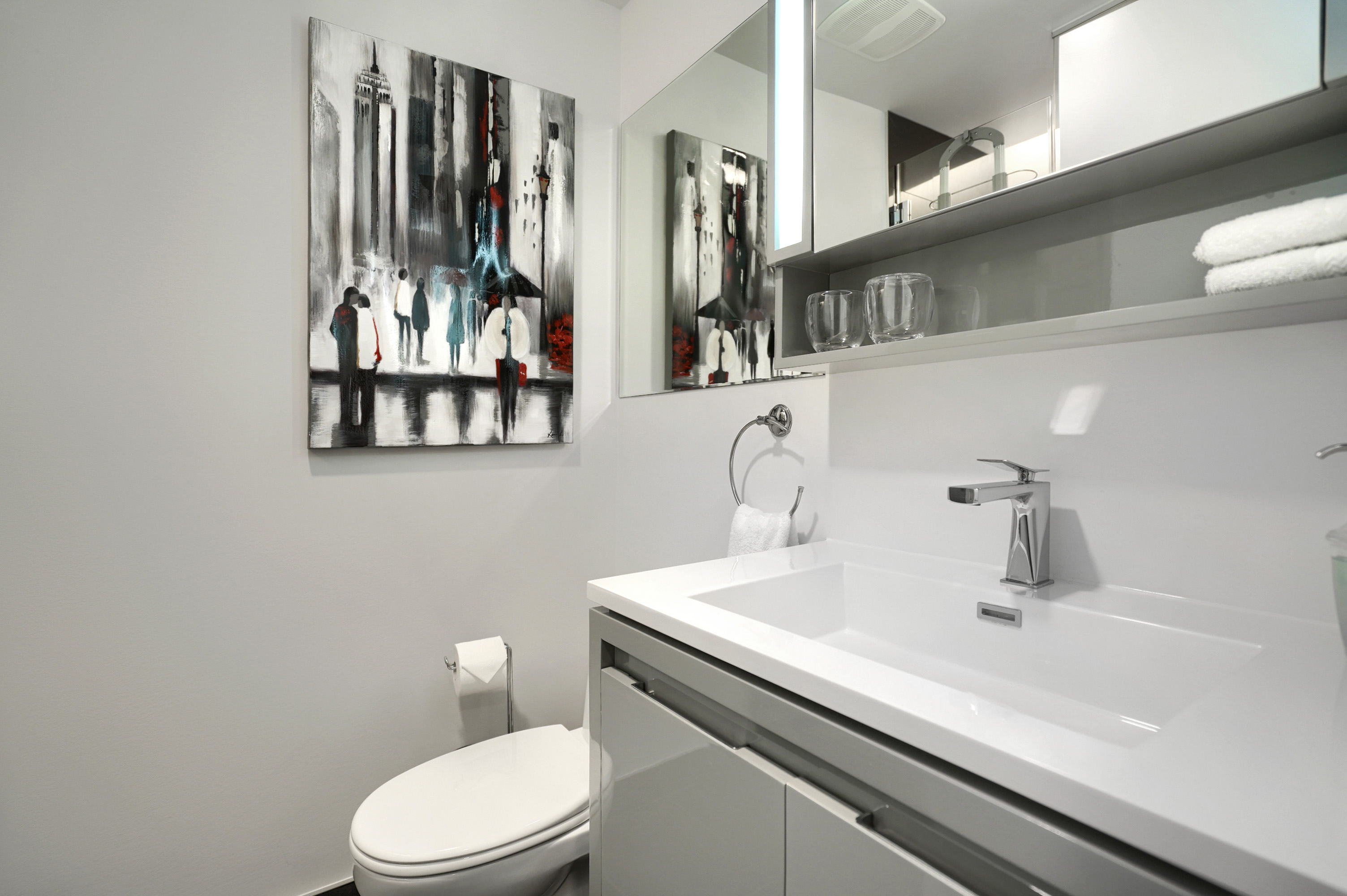 Gros plan du lavabo blanc surdimensionné de la salle de bain moderne et du robinet en acier inoxydable. Beaucoup de miroirs et d'éclairage. Accent de designer dans cette salle de bain dans ce condo meublé de luxe à Montréal 